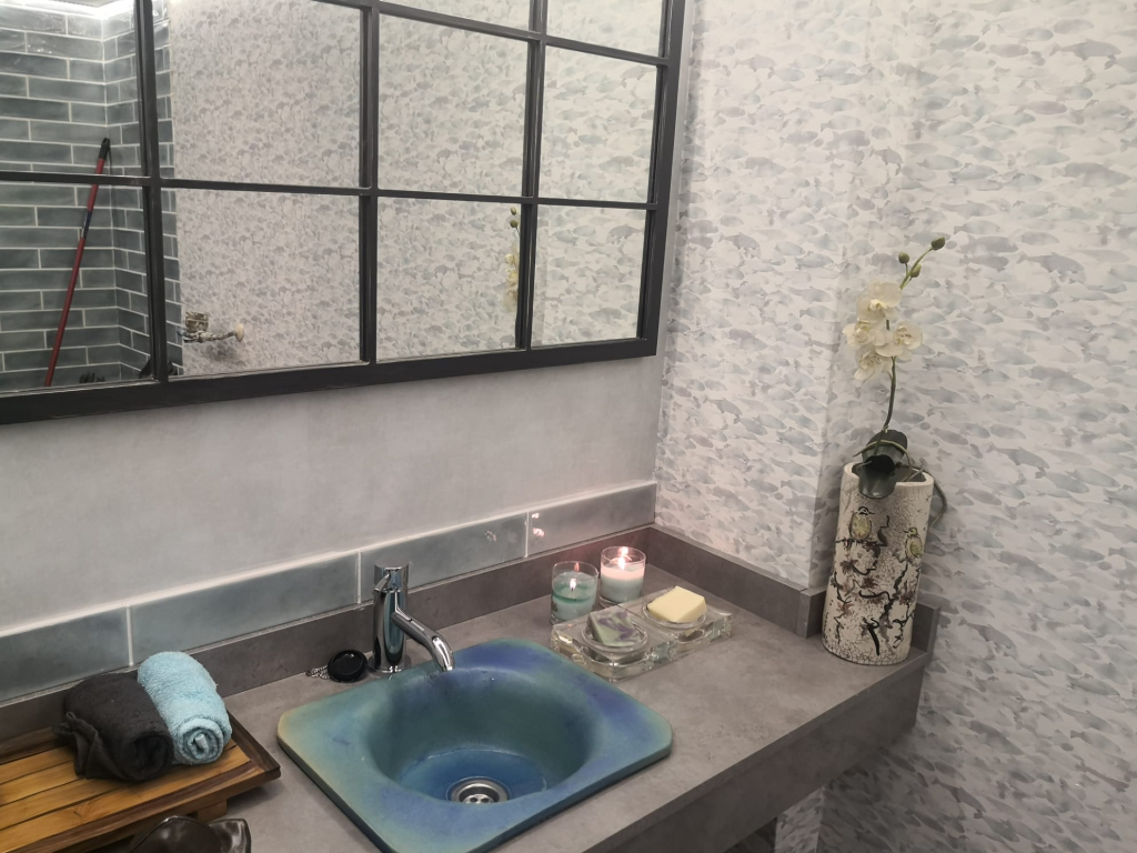 rediseño de baño con lavabo de piedra verde, con espejo con marco de madera. troqueldester en el barrio prosperidad en Madrid